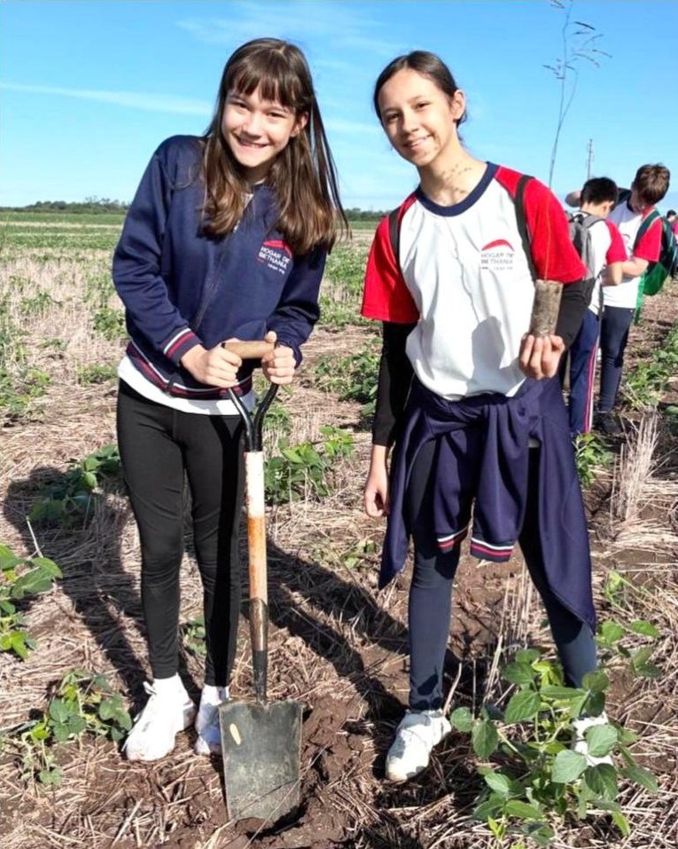 Dos estudiantes de Hogar de Bethania plantando árboles